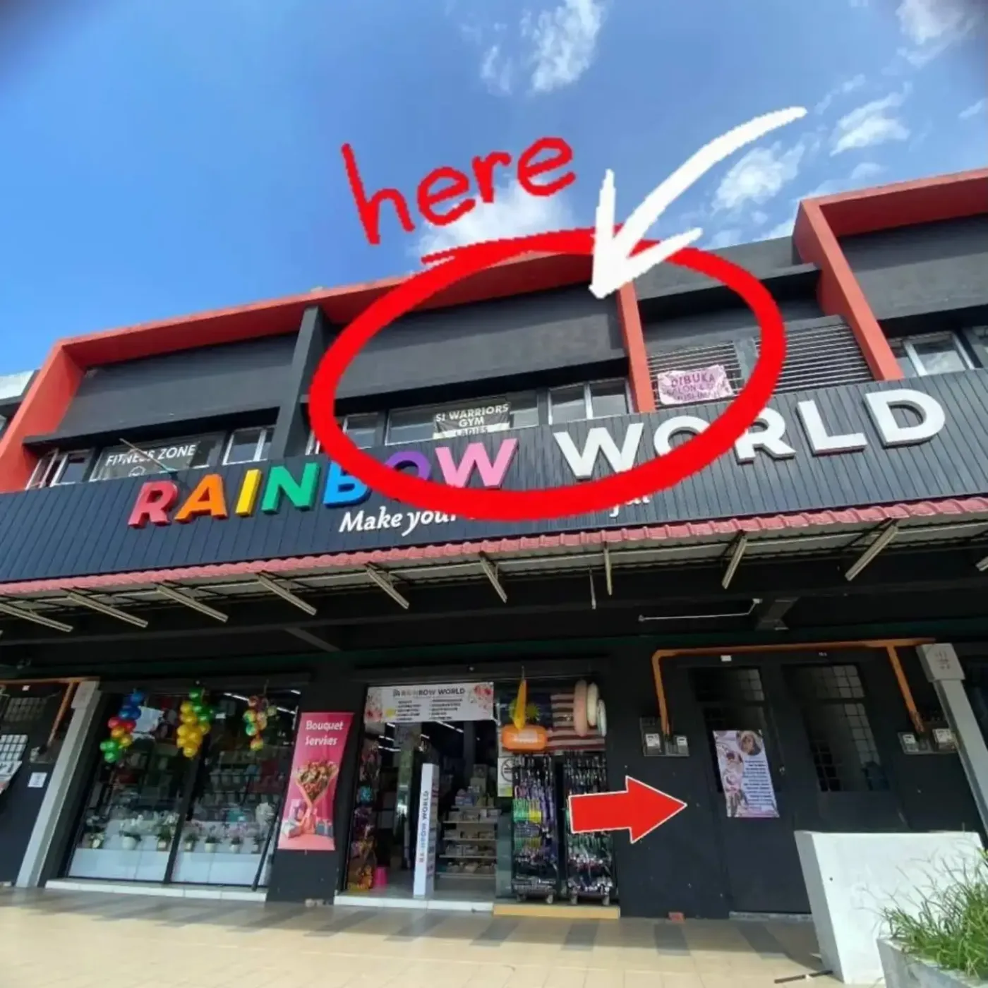 The shoplot row on Jalan RS 1 with Rainbow World signage. A red circle marks the first floor unit and an arrow points to the entrance door shared with Warrior Gym.